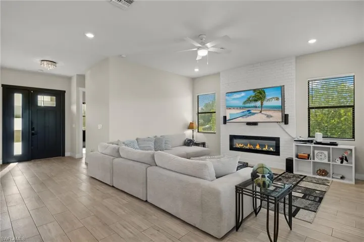Living room featuring a brick fireplace, light hardwood / wood-style floors, and ceiling fan