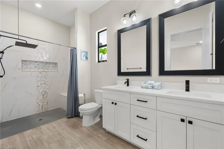 Bathroom with a shower with shower curtain, hardwood / wood-style flooring, vanity, and toilet