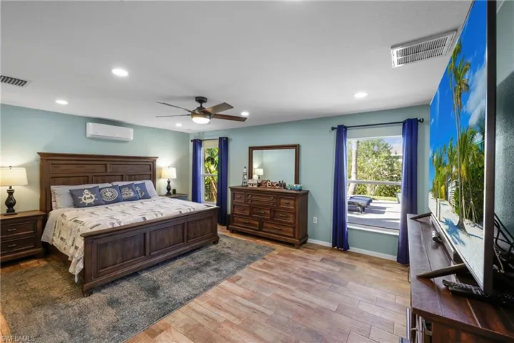 Bedroom with light hardwood / wood-style flooring, an AC wall unit, and ceiling fan