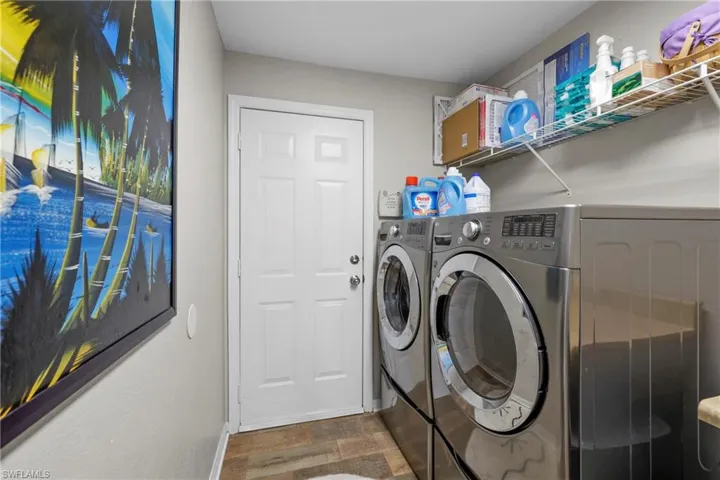 Clothes washing area with washing machine and dryer and dark hardwood / wood-style floors