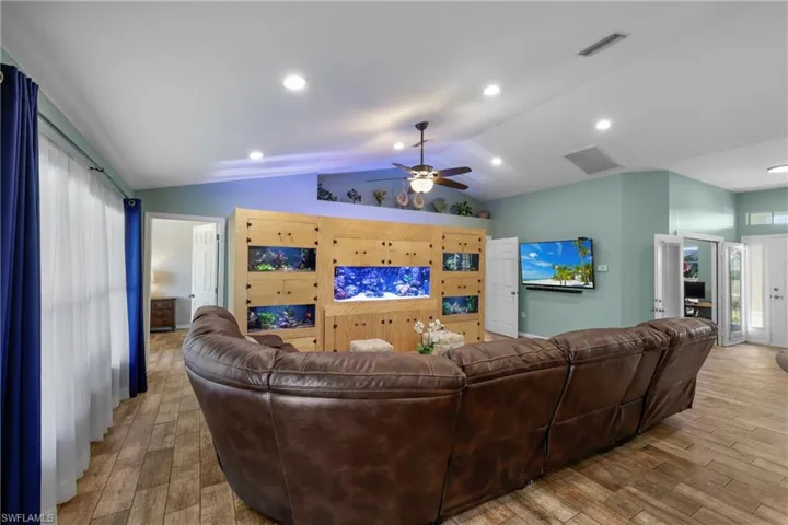 Living room with ceiling fan, vaulted ceiling, and light hardwood / wood-style flooring