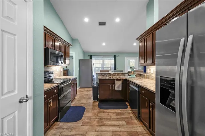 Kitchen featuring lofted ceiling, sink, kitchen peninsula, stainless steel appliances, and decorative backsplash