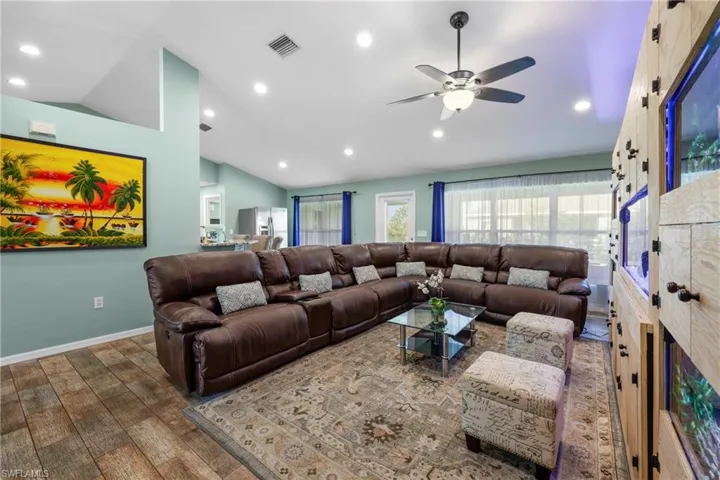 Living room featuring vaulted ceiling, dark wood-type flooring, and ceiling fan
