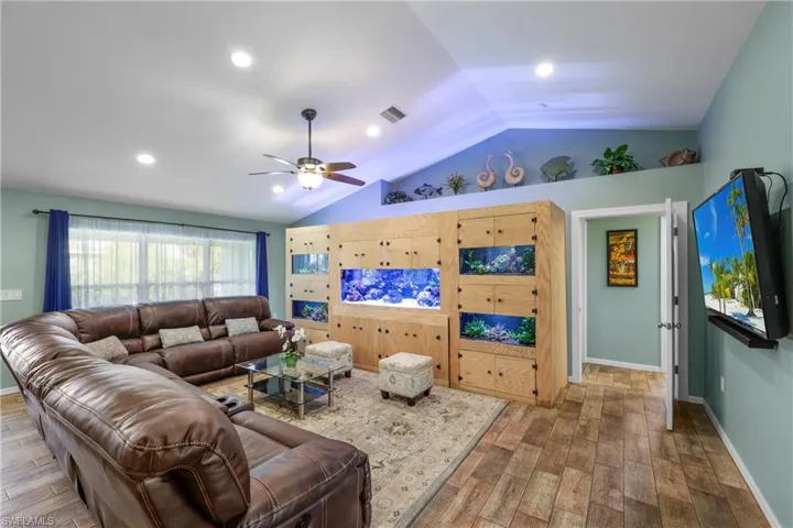 Living room with lofted ceiling, hardwood / wood-style flooring, and ceiling fan