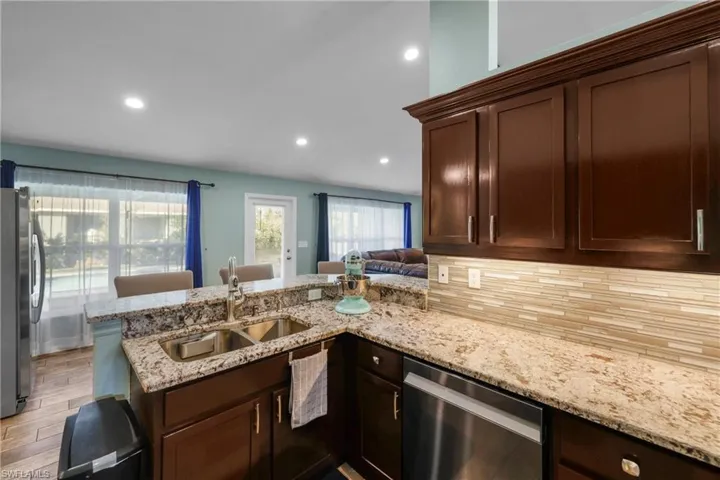 Kitchen with sink, backsplash, kitchen peninsula, stainless steel appliances, and light hardwood / wood-style flooring