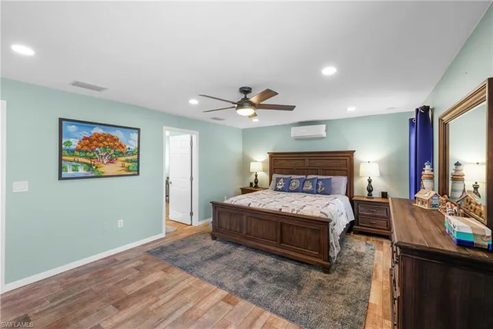 Bedroom featuring a wall mounted AC, ceiling fan, and light hardwood / wood-style flooring