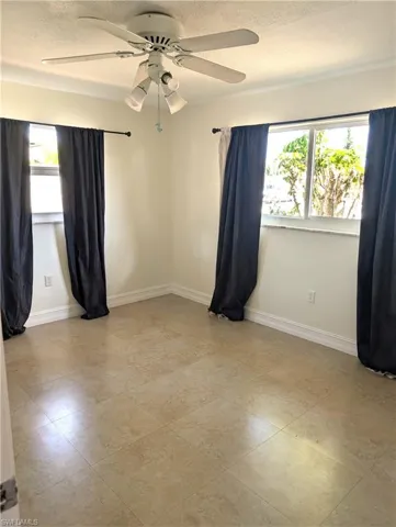 2nd bedroom with light tile patterned floors, ceiling fan, and baseboards
