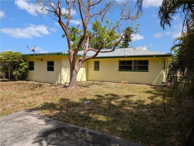 Rear view of house with stucco siding and a yard