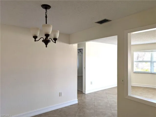 Dining area with light tile-patterned floors, with an open look into the living room