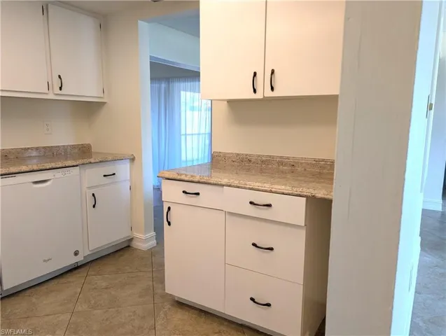 Kitchen featuring light tile patterned floors, white cabinetry, and dishwasher
