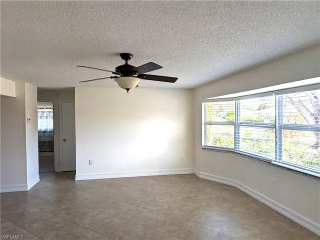 Living room room featuring light tile patterned floors, a ceiling fan, and bay window with plenty of natural light