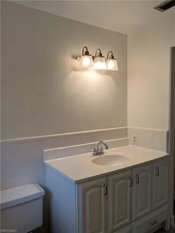Bathroom featuring vanity, toilet, shower and a wainscoted wall