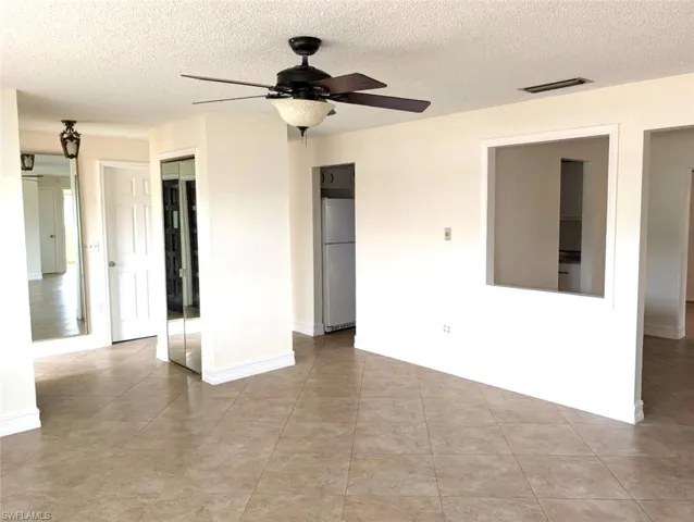 Living room with a with a a view of the main floor plan, ceiling fan, and light tile patterned floors