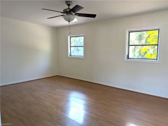 Empty room with wood finished floors, a ceiling fan, and baseboards