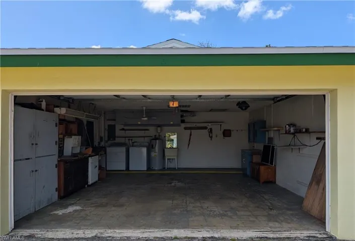 Garage featuring a sink, washing machine and clothes dryer, electric panel, and electric water heater