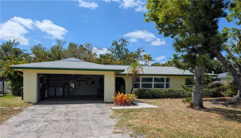 Ranch-style house with a front lawn, stucco siding, driveway, and an attached garage