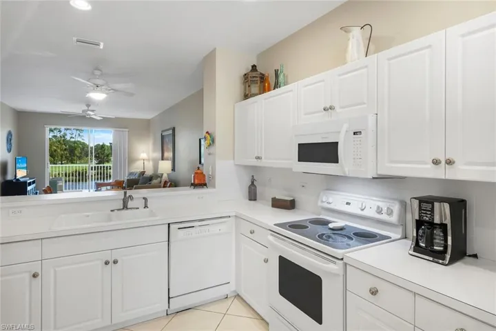 Kitchen with white appliances, white cabinetry, light countertops, open floor plan, and recessed lighting