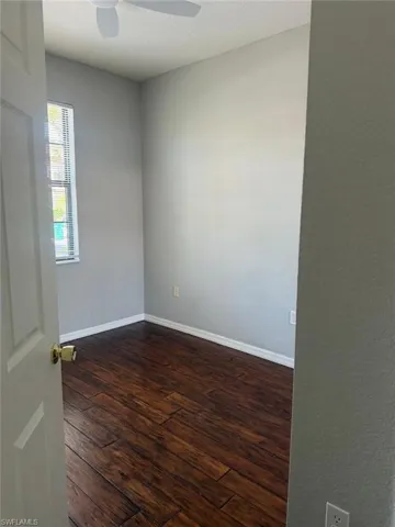 Room featuring wood-look flooring, light gray walls, a window with blinds, and a ceiling fan