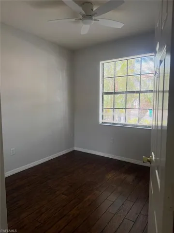 This room features dark wood flooring, light-colored walls, and a window with blinds