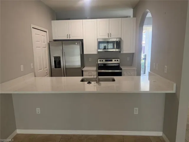 The kitchen features white cabinetry, stainless steel appliances, and light-colored countertops