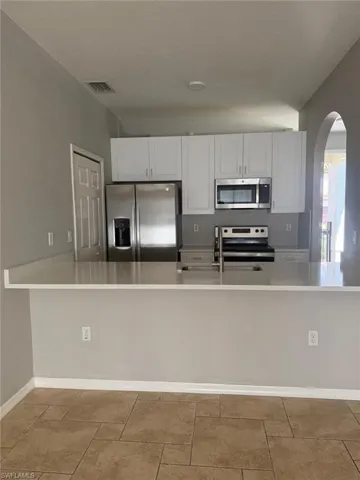 Kitchen featuring white cabinetry, stainless steel appliances, and a breakfast bar with a light-colored countertop