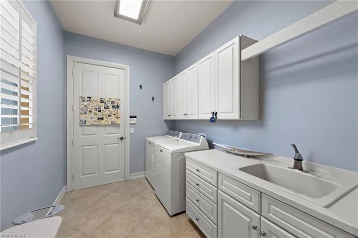 Laundry room with cabinet space, washer and clothes dryer, and light tile patterned flooring