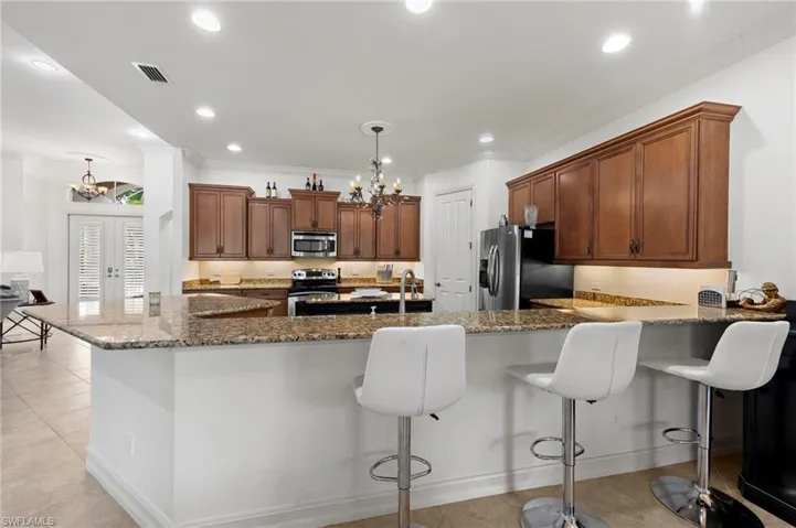Kitchen featuring a chandelier, a breakfast bar, dark stone counters, stainless steel appliances, and recessed lighting