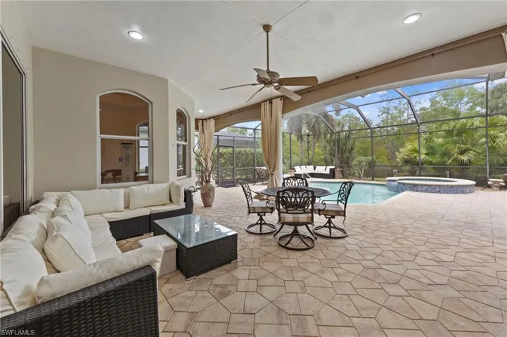 View of patio with a ceiling fan, a sunroom, an outdoor hangout area, a pool with connected hot tub, and a lanai