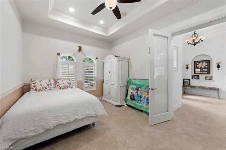 Bedroom with crown molding, a tray ceiling, ceiling fan, recessed lighting, and light tile patterned flooring