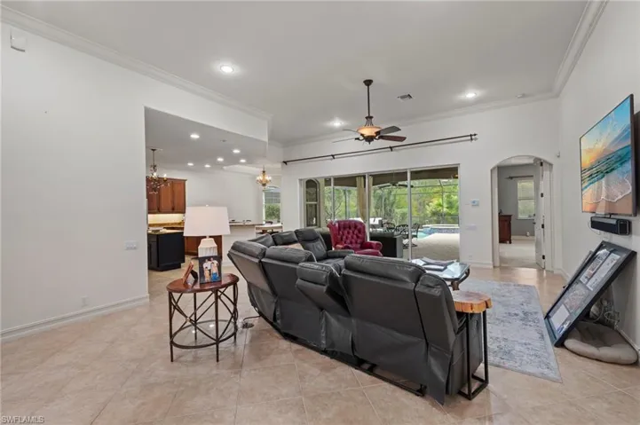 Living room featuring crown molding, recessed lighting, arched walkways, ceiling fan, and light tile patterned floors