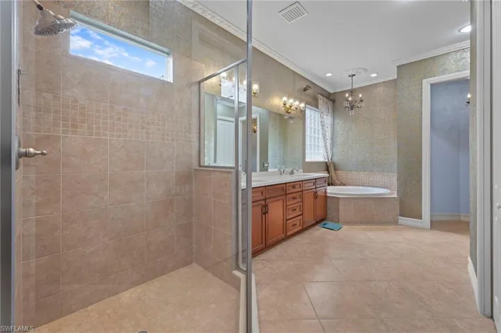 Full bathroom with a stall shower, a bath, double vanity, ornamental molding, and recessed lighting