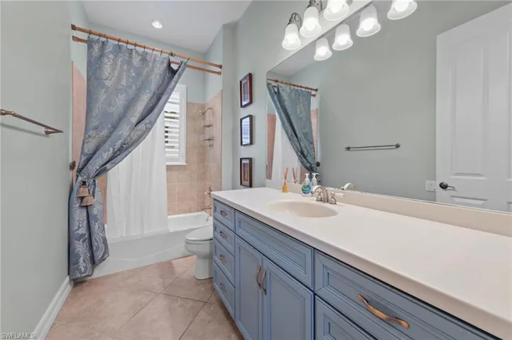 Full bathroom with shower / bath combination with curtain, vanity, and light tile patterned floors