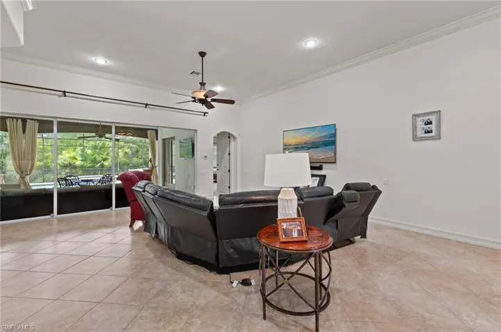 Living room featuring crown molding, arched walkways, light tile patterned flooring, a ceiling fan, and recessed lighting