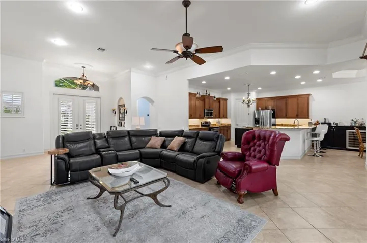 Living room with a chandelier, ornamental molding, arched walkways, beverage cooler, and recessed lighting