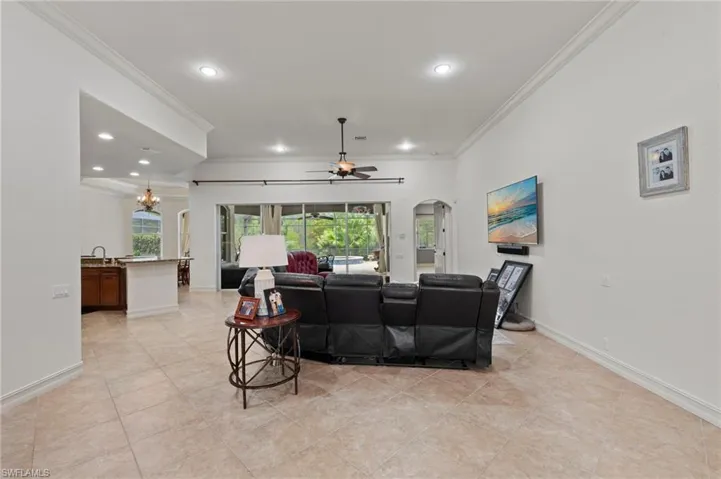 Living area with crown molding, arched walkways, a chandelier, recessed lighting, and a ceiling fan