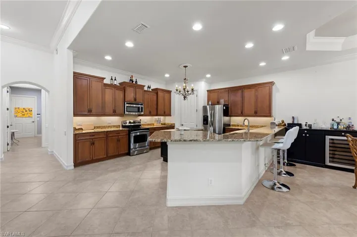 Kitchen featuring a breakfast bar, arched walkways, a peninsula, crown molding, and appliances with stainless steel finishes