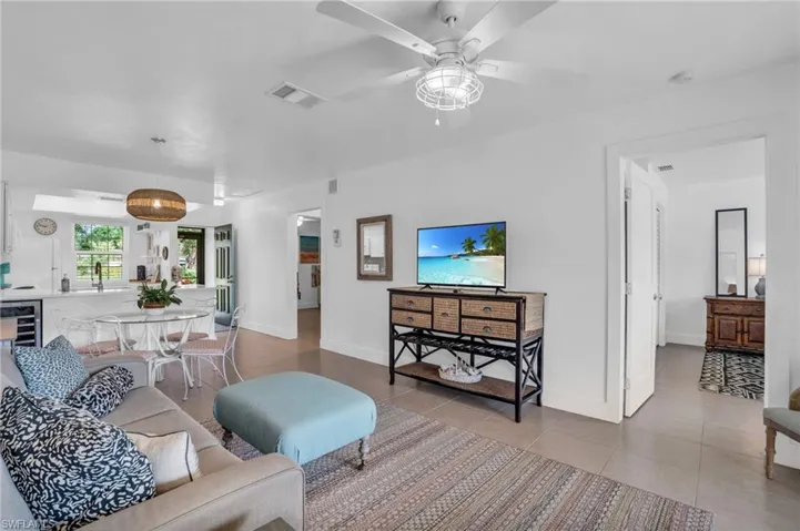 Tiled living room with ceiling fan, beverage cooler, and sink
