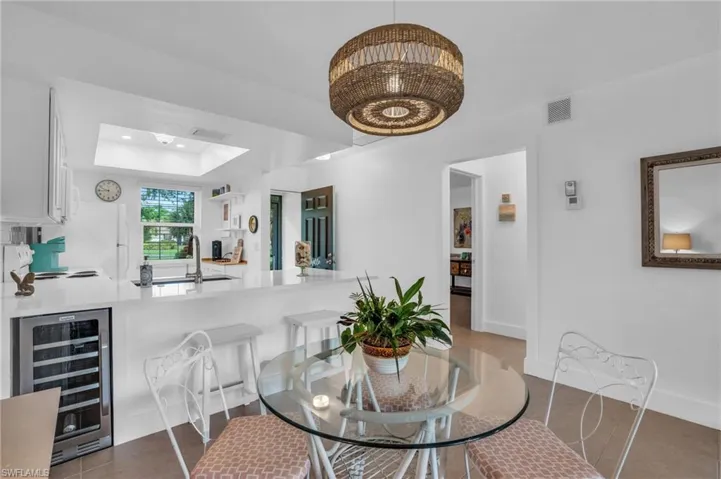 Tiled dining room featuring wine cooler, sink, a raised ceiling, and a skylight