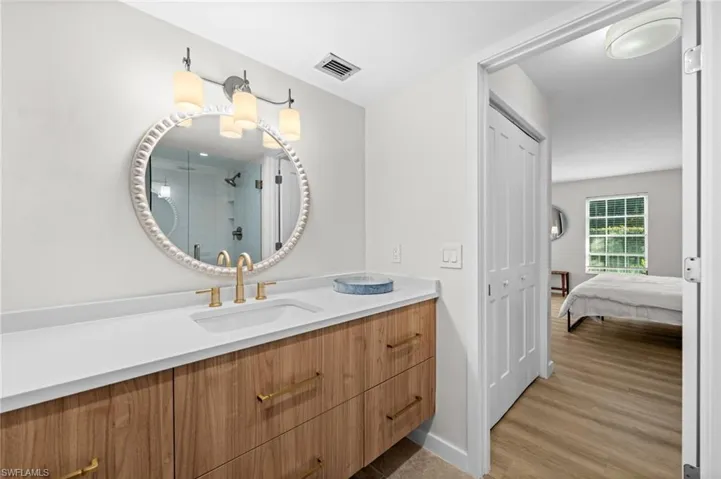 Ensuite bathroom featuring vanity, a stall shower, and light wood-type flooring