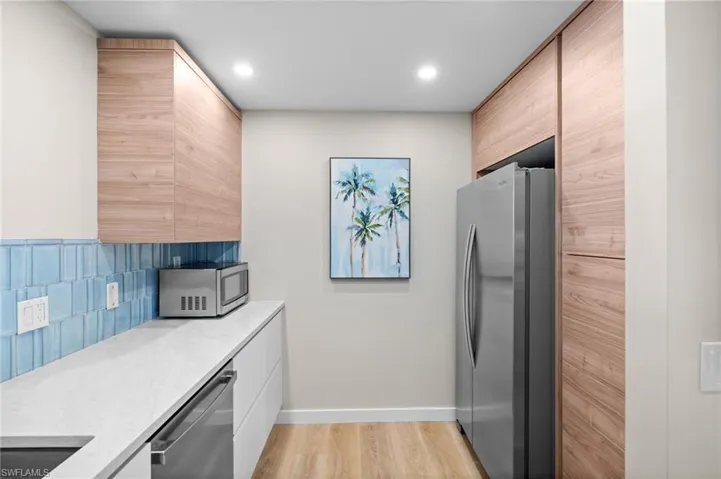 Kitchen with appliances with stainless steel finishes, light stone countertops, light wood-style flooring, modern cabinets, and recessed lighting