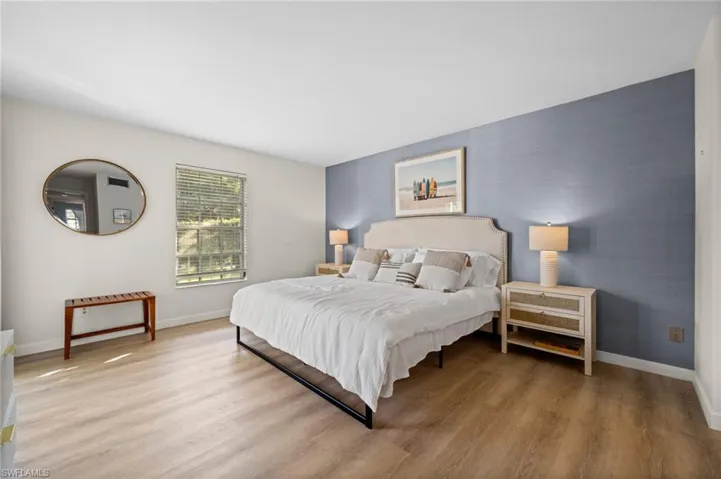 Bedroom with an accent wall and wood finished floors