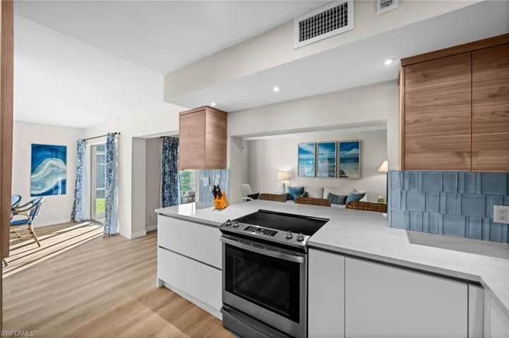 Kitchen featuring stainless steel electric range, modern cabinets, light wood-type flooring, light stone counters, and white cabinetry