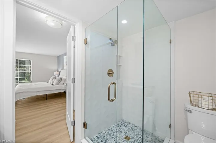 Ensuite bathroom featuring a shower stall, wood finished floors, and recessed lighting