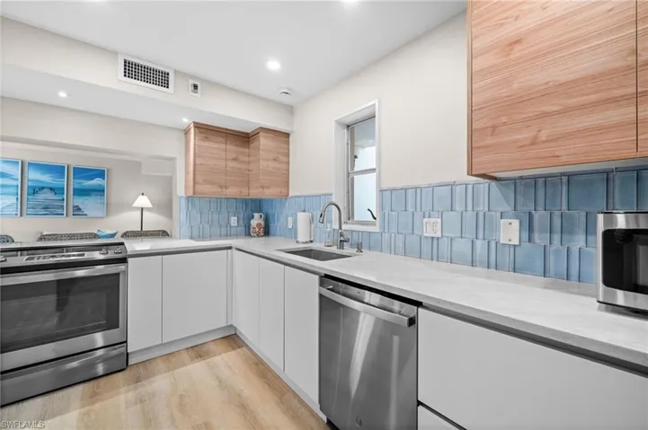 Kitchen with appliances with stainless steel finishes, light wood-type flooring, modern cabinets, decorative backsplash, and recessed lighting