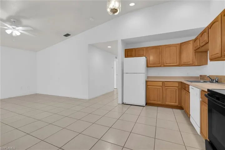 Spacious kitchen featuring wood cabinetry, white appliances, and a double basin sink