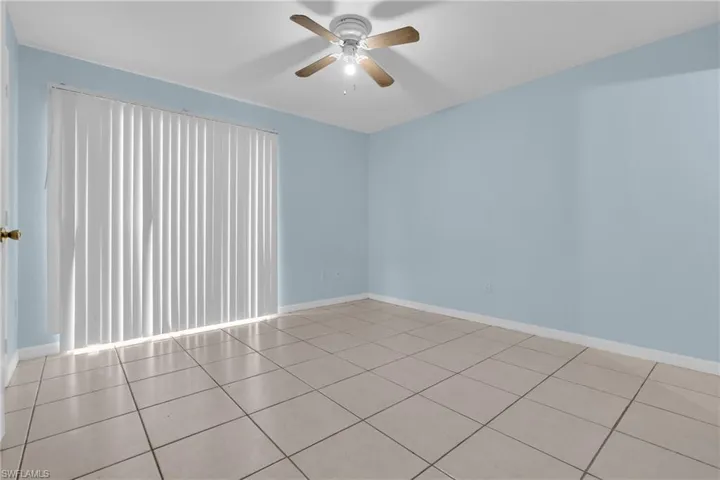 Spacious room featuring light blue walls, ceramic tile flooring, and a ceiling fan with integrated lighting