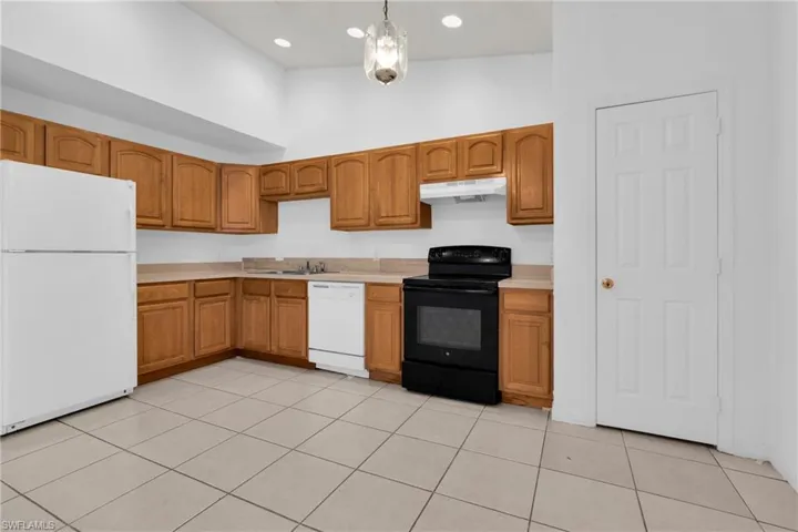 Kitchen featuring wood-finish cabinetry, light-toned countertops, and tile flooring