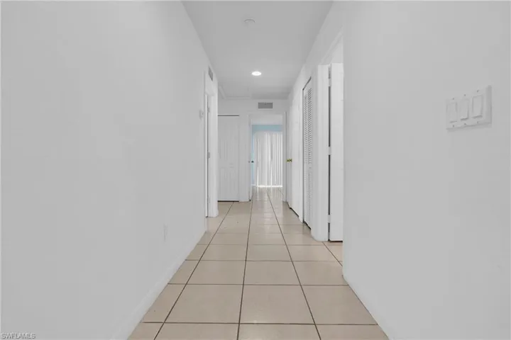 Hallway featuring neutral-toned tile flooring, white walls, and recessed lighting