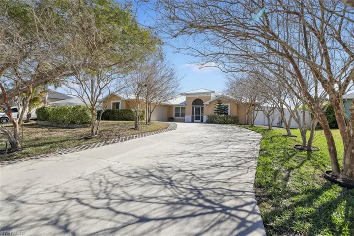 View of front facade with concrete driveway, stucco siding, and a front yard