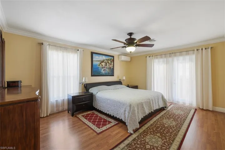 Bedroom with crown molding, light wood-style floors, and a ceiling fan